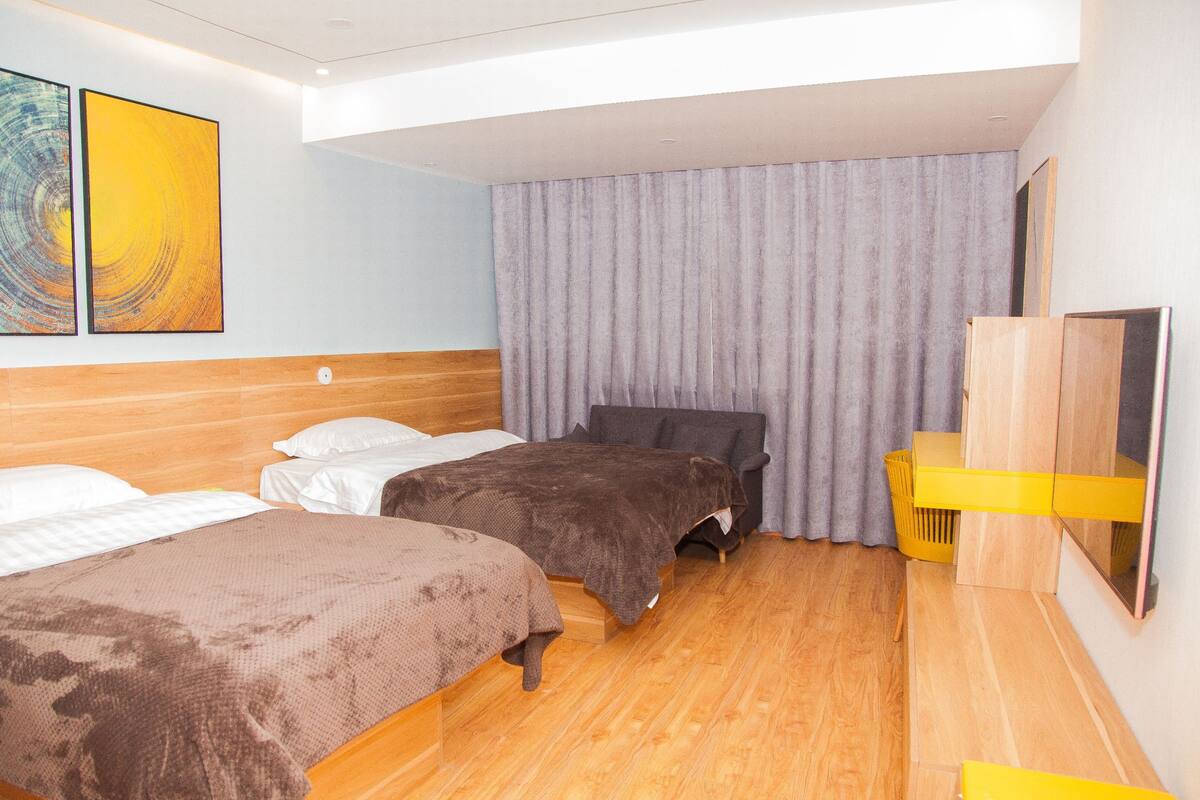 A hotel room with two beds, a wooden headboard, a large window, and a mirror.