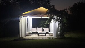 Un gazebo con tenda, tende bianche e una panca.