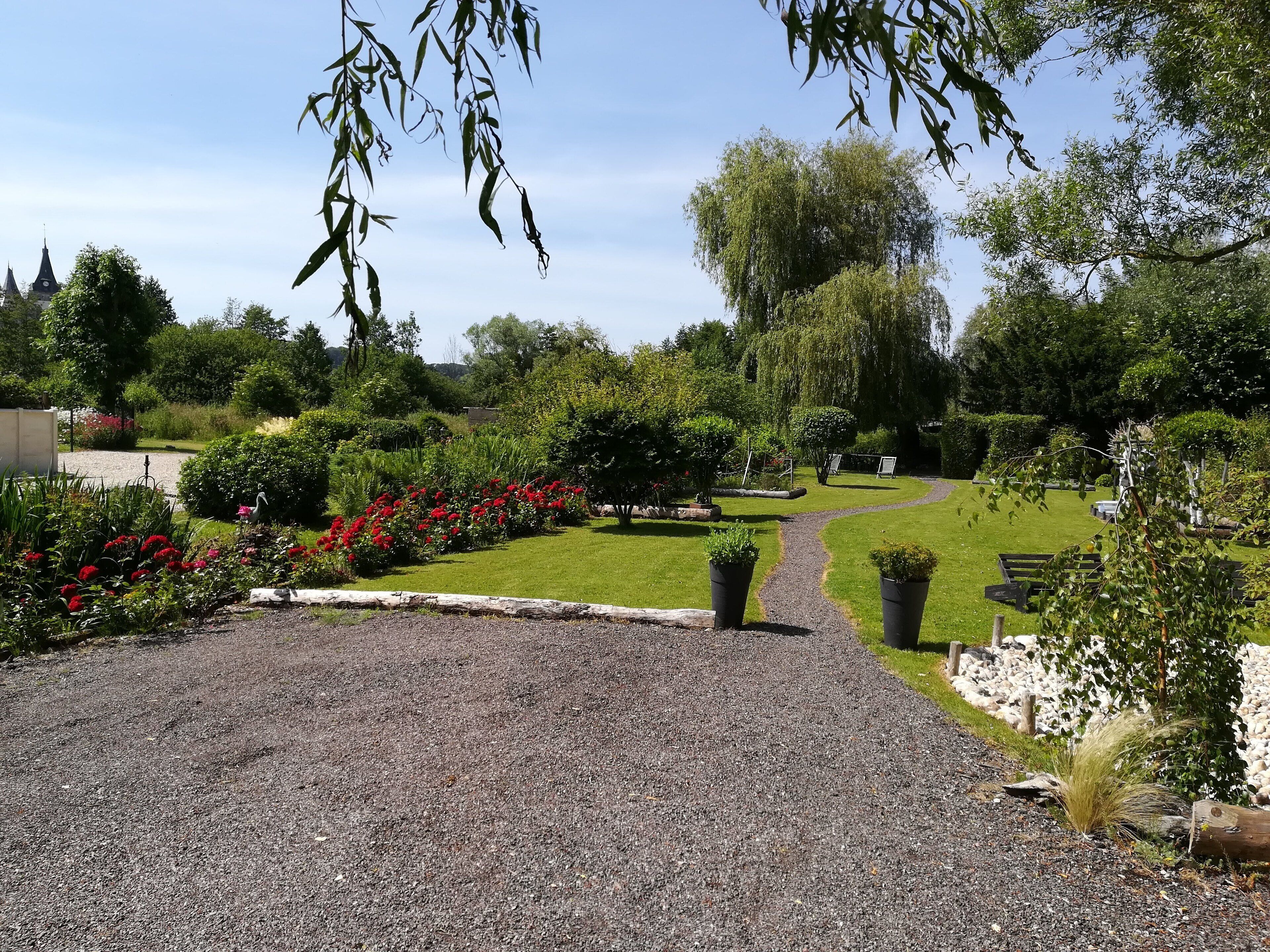 Un sendero de jardín que conduce a una zona de estar con bancos y plantas en macetas.