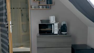 Une chambre compacte équipée d’une douche, d’un four à micro-ondes, d’une machine à café et d’un petit placard.