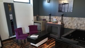 A modern living area with a fireplace, two purple chairs, a coffee table, and a kitchen in the background. - Cléome (Arques-la-Bataille)