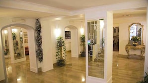 A spacious hotel lobby with a polished wooden floor, multiple arches, and potted plants. - Hotel Cecil (Rome)