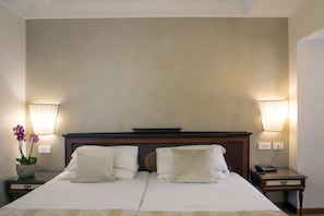 A hotel room with a large bed, two bedside lamps, a nightstand with a phone, and a potted plant. - Hotel Cecil (Rome)
