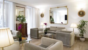 Ein modernes Wohnzimmer mit einer Sofagarnitur, einem Couchtisch und zwei Lampen. An der Wand hängt ein großer Spiegel und an der Seite steht ein Blumentopf.