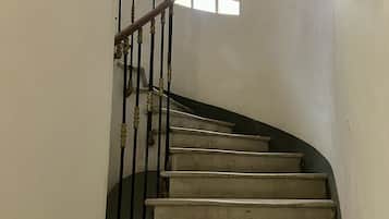 A spiral staircase with a handrail and balusters, leading to a landing with a window.