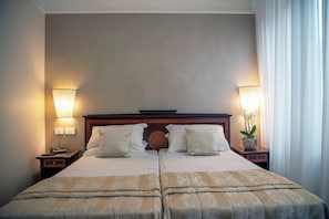 A double bed with a wooden headboard, two bedside tables with lamps, and a potted plant on the right side. - Hotel Cecil (Rome)