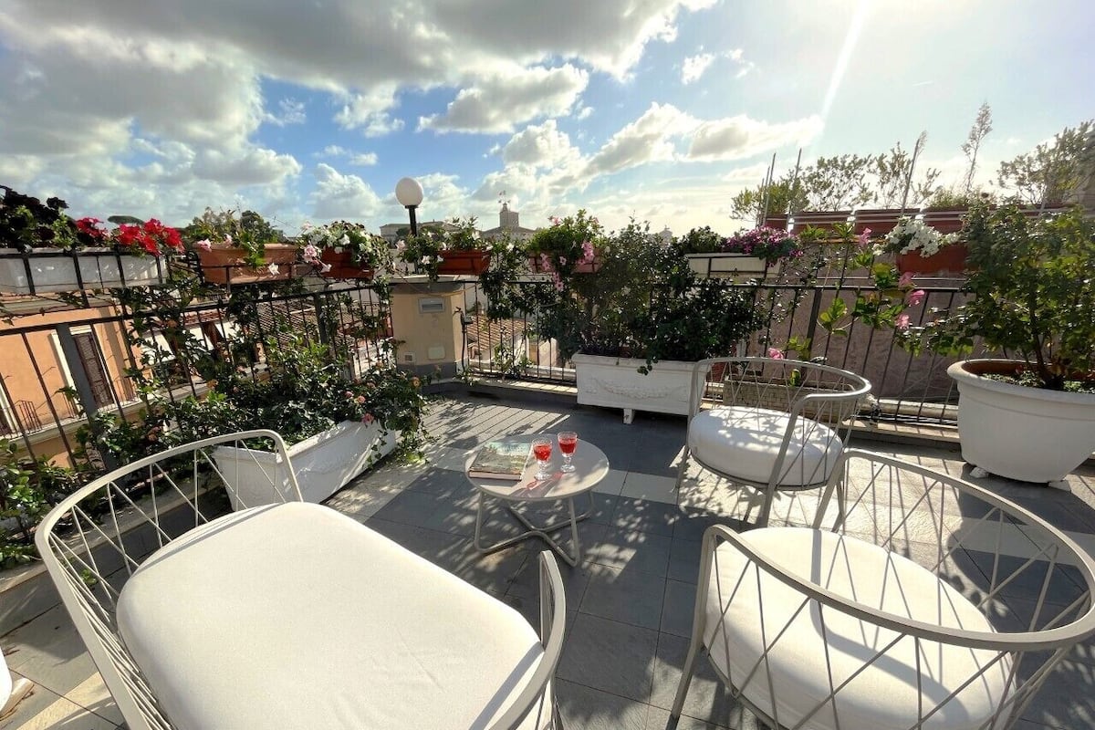 A rooftop terrace with outdoor seating, potted plants, and a view of the cityscape.