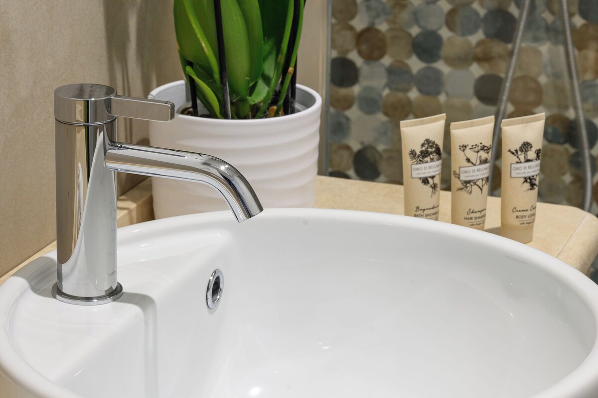 A bathroom with a white sink, a potted plant, and toiletries.