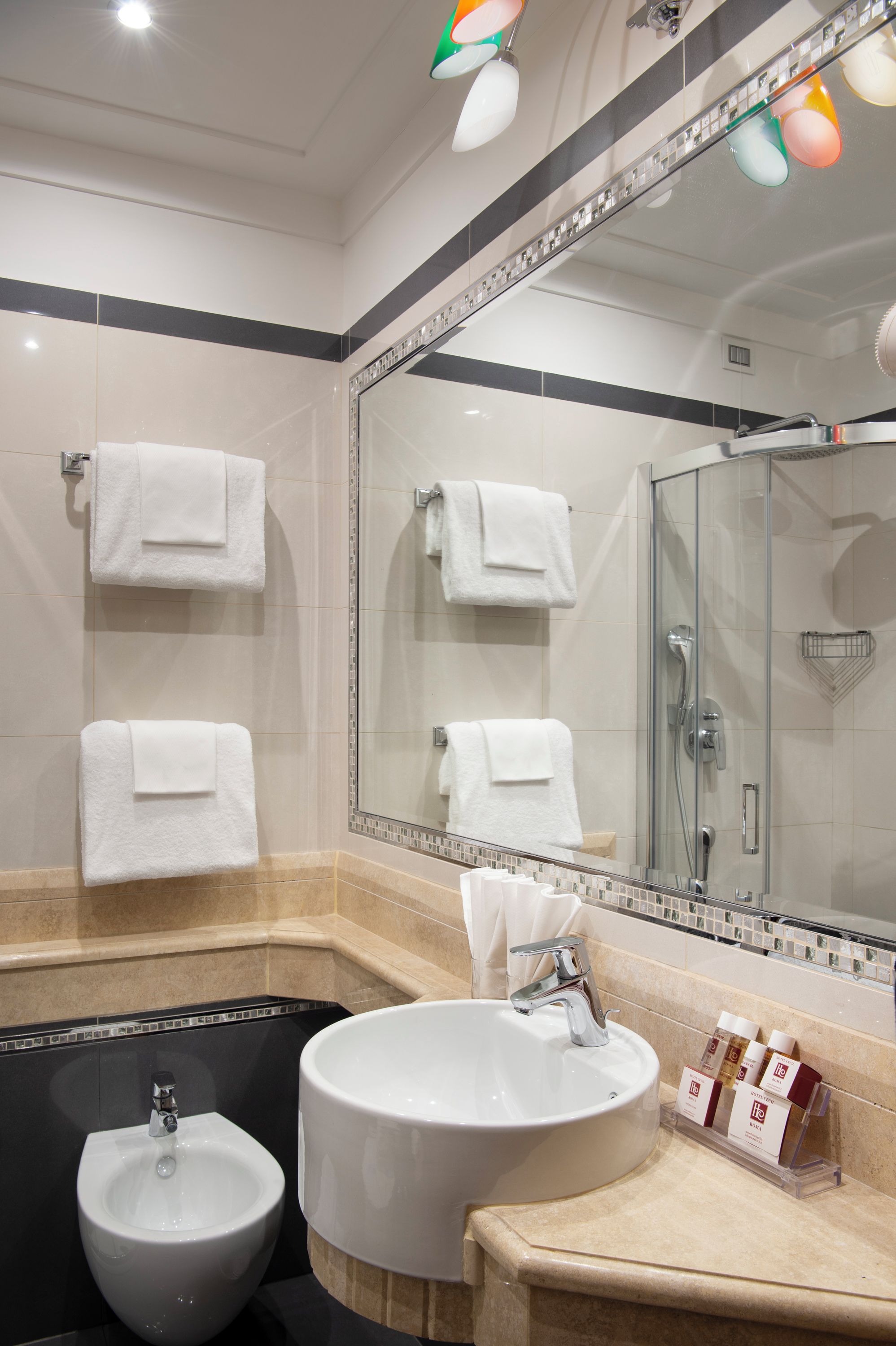 A modern bathroom with a bidet, a large mirror, and a glass shower enclosure.