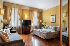 A hotel room with a bed, a sofa, a TV, a dresser, and curtains. - Hotel Cecil (Rome)