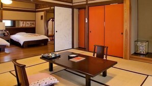 A traditional Japanese-style room with tatami flooring, a low table with cushions, a bed, and sliding doors. - Hirayama Onsen Yama Futokoro no Yado Ichiboku Isso (Yamaga)
