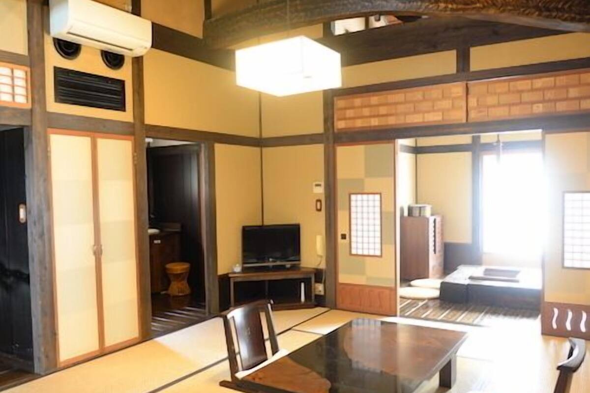Ein traditioneller japanischer Raum mit Tatami-Bodenbelag, einem niedrigen Tisch und einem Fernseher.