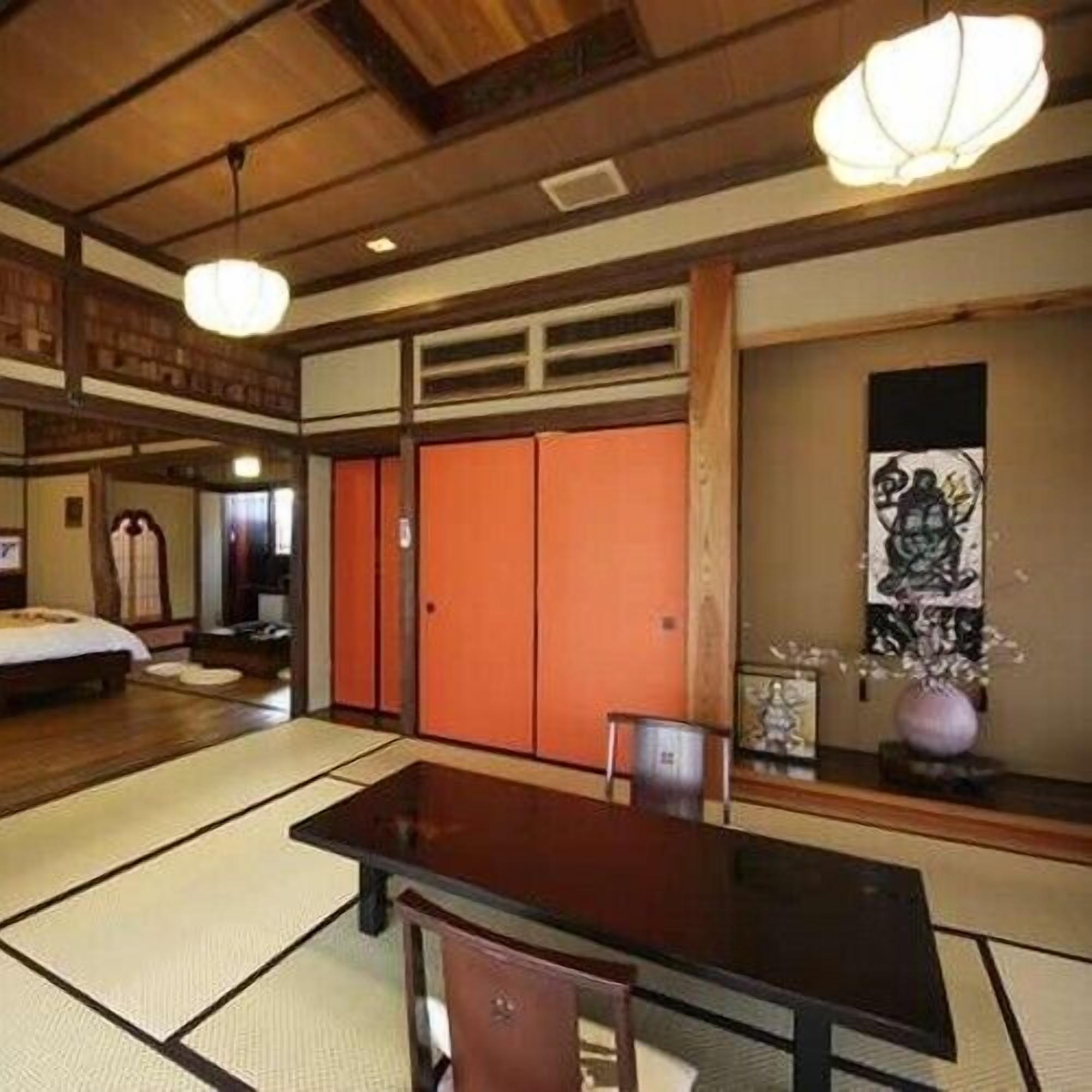A traditional Japanese room with tatami flooring, a low table, a chair, and a sliding door.