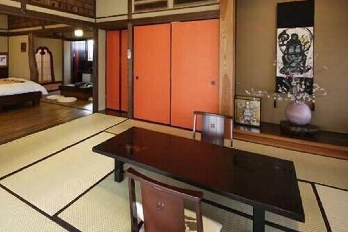 Ein traditioneller japanischer Raum mit Tatami-Bodenbelag, einem niedrigen Tisch, einem Stuhl und einer Schiebetür.