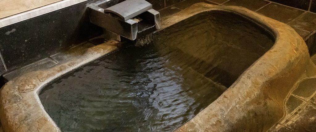 Una bañera de piedra con agua fluyendo.