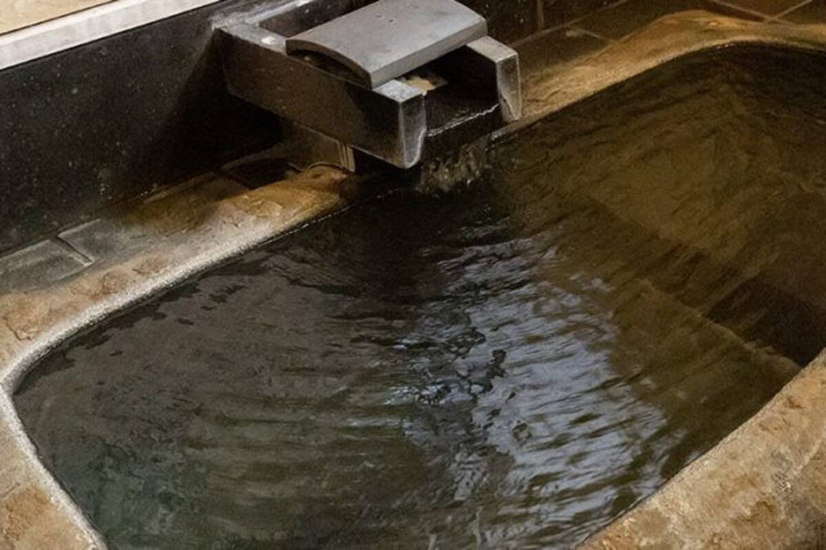 Eine Steinebadewanne, in die Wasser fließt.