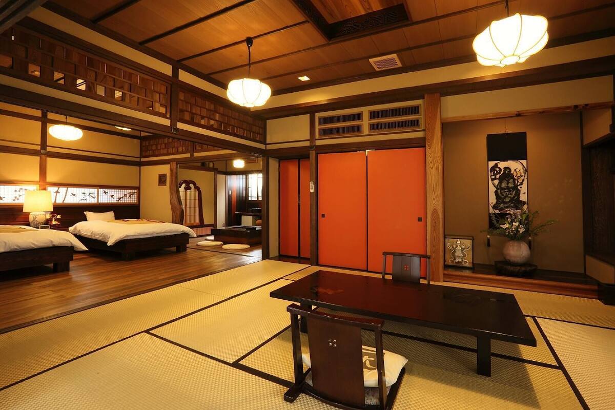 Ein traditionell gestalteter japanischer Raum mit Tatami-Boden, niedrigem Tisch und zwei Betten, sowie verschiebbaren Türen.