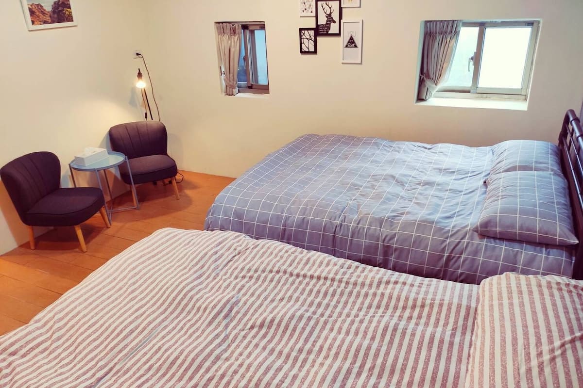 Un dormitorio con una cama grande, dos sillas, una mesita y una ventana.