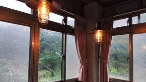 Una habitación con ventanas amplias, cortinas y lámparas colgantes.