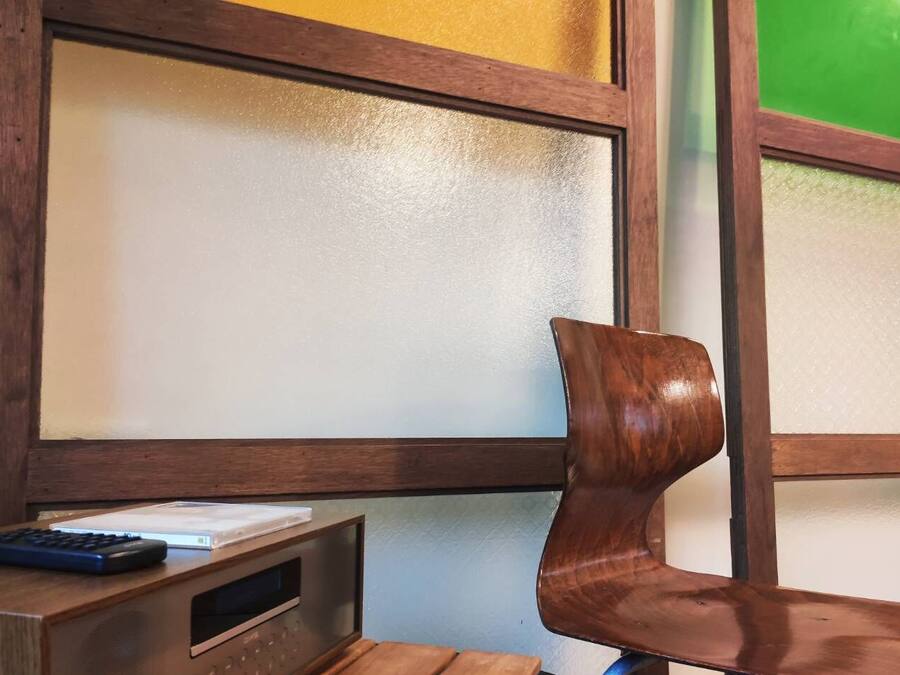 A wooden chair with a backrest and a table with a remote control.