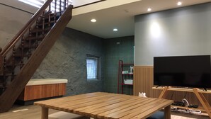 Una sala de estar moderna con una escalera de madera, un televisor de pantalla plana y una mesa de madera.