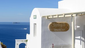 A reception sign for Strogili on a white building with a view of the sea and a ship in the distance. - Strogili Traditional Houses (Santorini)