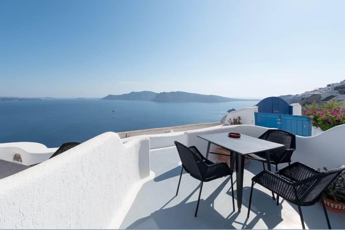 A terrace with a table and chairs overlooking the sea.