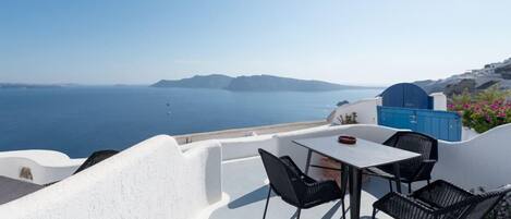Une terrasse avec une table et des chaises donnant sur la mer.