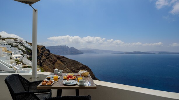 A table with breakfast items and a view of the sea. - Strogili Traditional Houses (Santorini)