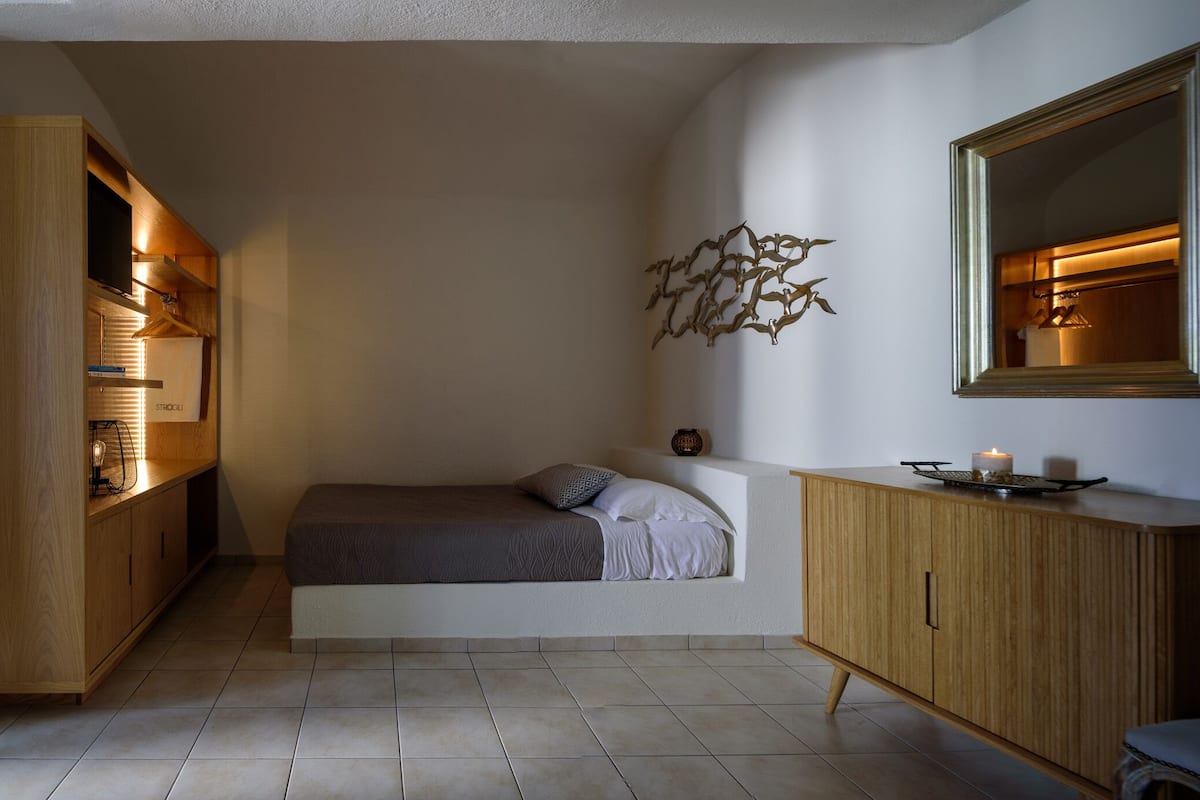 A bedroom with a bed, a wardrobe, a mirror, and a door.