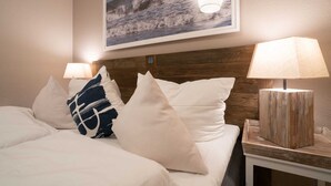 Ein Hotelzimmer mit einem Bett, zwei Nachttischlampen und einem Bilderrahmen mit einer Darstellung einer Welle an der Wand.