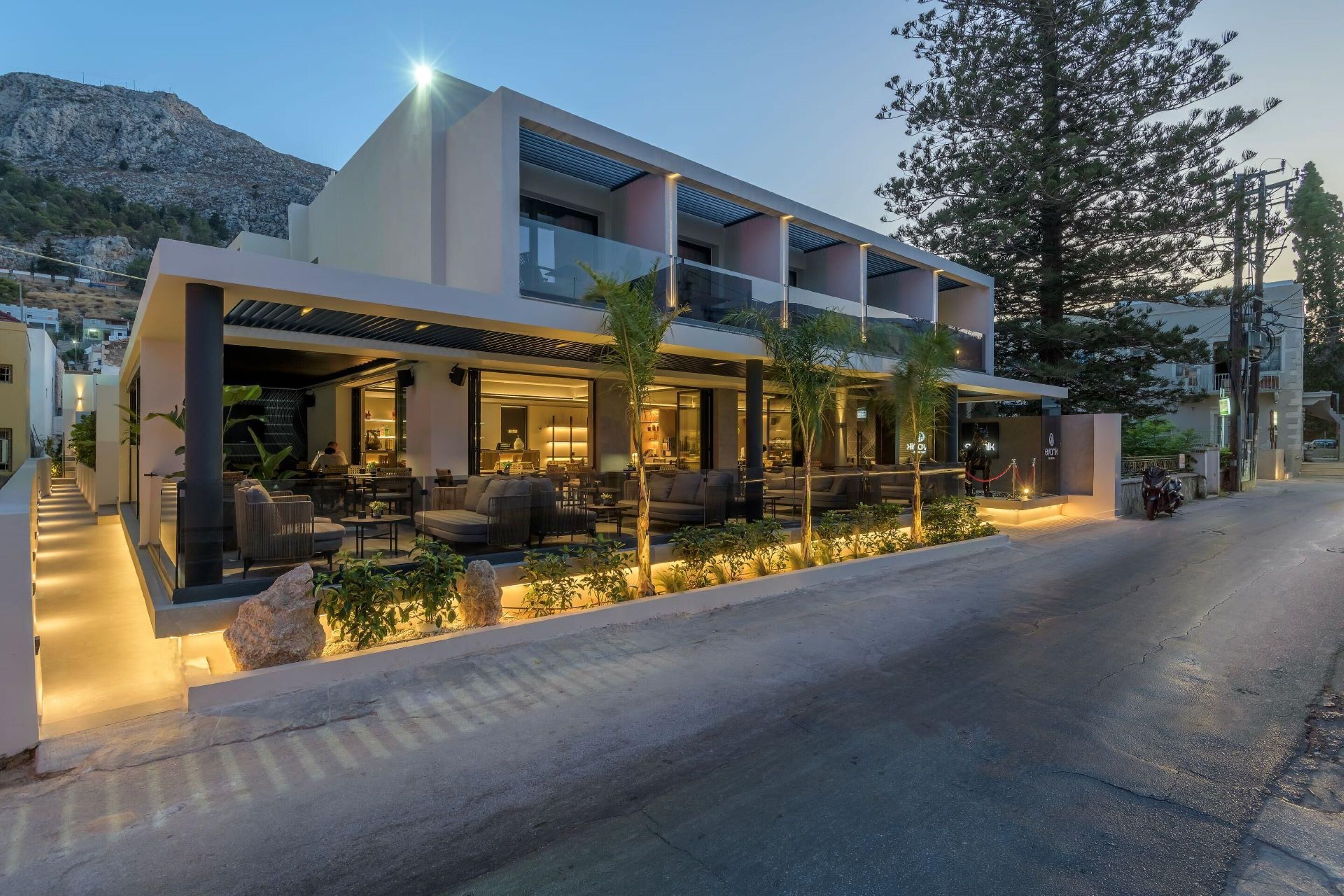 Un hotel moderno con un área de estar al aire libre techada, varios balcones y vistas del paisaje circundante.