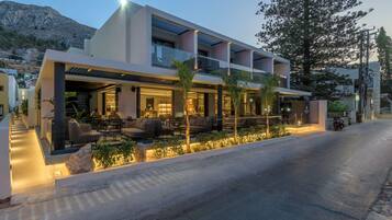 Un hotel moderno con un área de estar al aire libre techada, varios balcones y vistas del paisaje circundante.