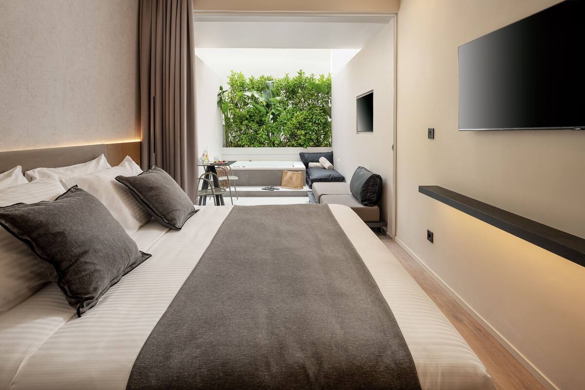 Ett modernt hotellrum med en stor säng, ett skrivbord och utsikt över grönområden genom ett fönster.