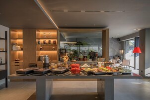 Habitación de hotel moderna con bufé de desayuno, estantes de madera y vistas al exterior.