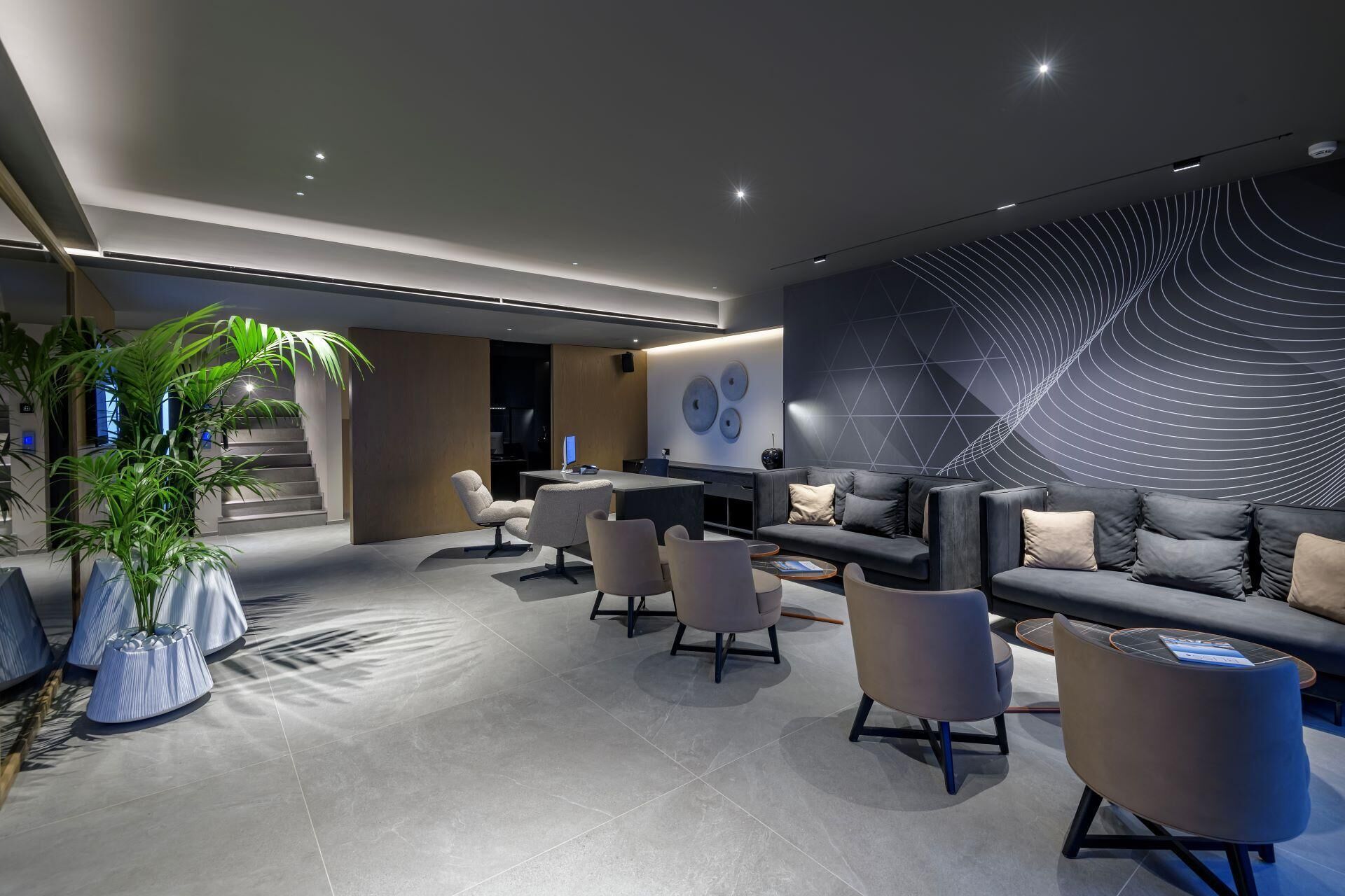 Uma sala de estar moderna com sofá, poltronas, mesa de centro e uma planta grande.