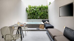 A modern outdoor living area with a dining table, chairs, a sofa, and a hot tub. - Evanik Chic Hotel (Kalymnos)