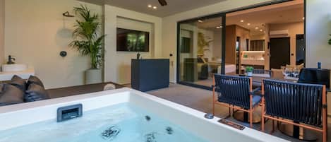 A modern bathroom with a bathtub, a ceiling fan, and a potted plant.