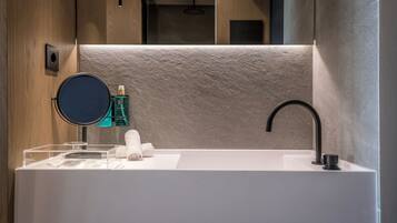 A modern bathroom with a large white sink, a round mirror, and a black faucet.