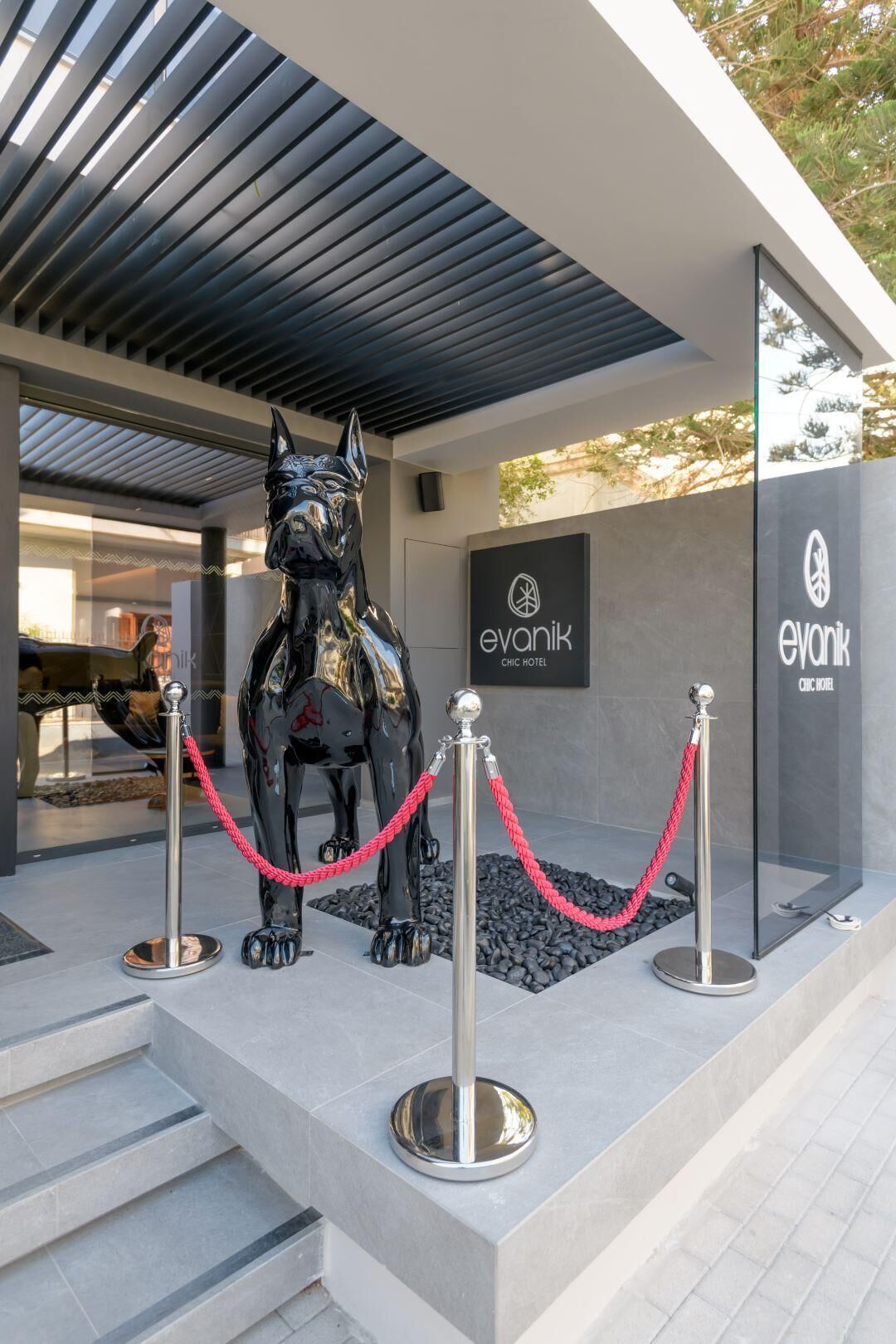 A modern building with a glass facade, a metal sculpture of a wolf, and a sign for 'evanik chic hotel'.