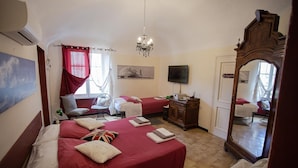 Habitación de hotel con dos camas, un televisor, una araña y un espejo grande.