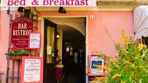 Fachada con un letrero que dice 'Bed & Breakfast', un letrero de 'BAR' y un letrero de 'BISTROT'.
