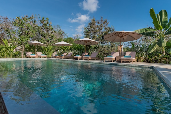 Una piscina al aire libre, sillones reclinables de piscina