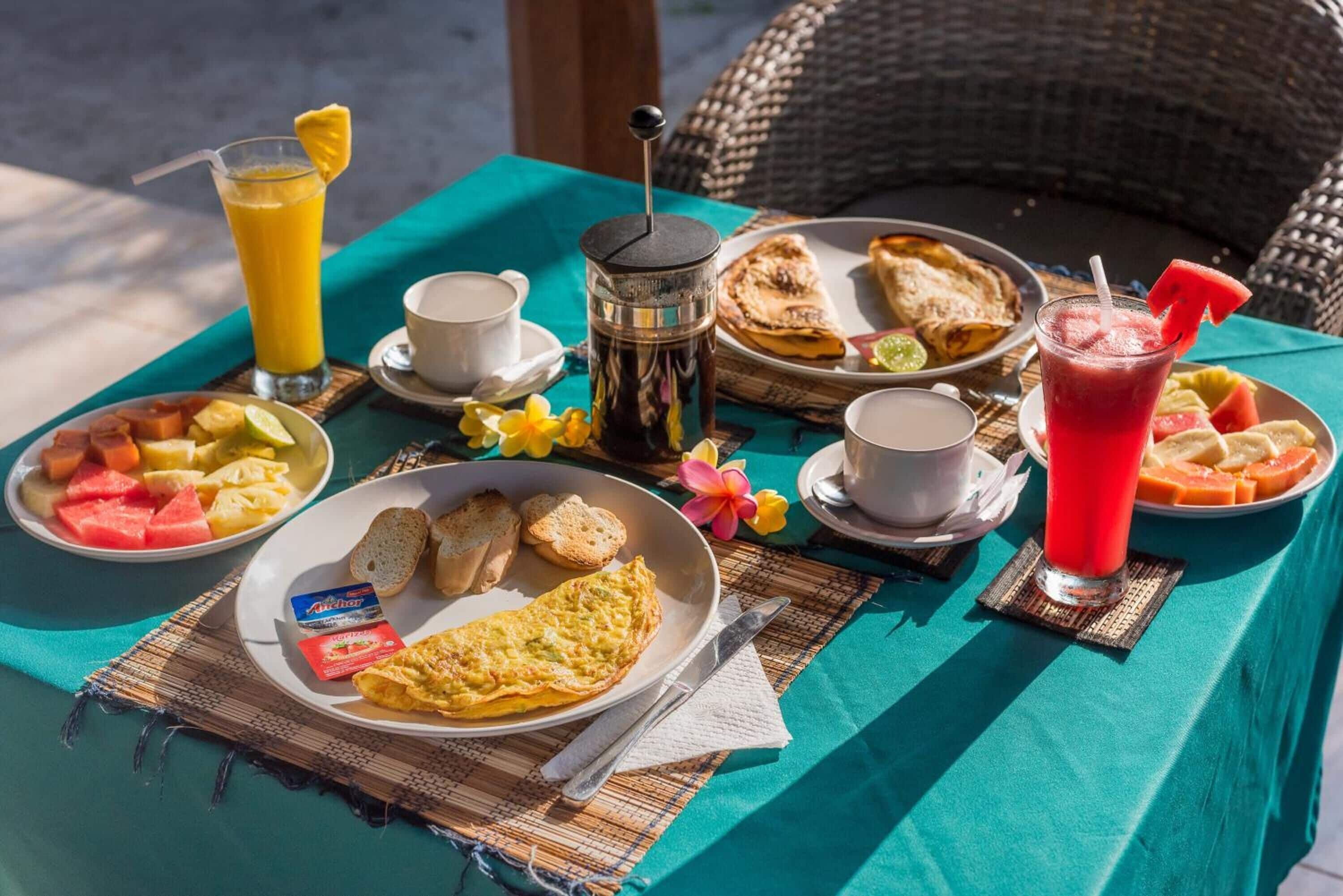 En morgenmadsopsætning med forskellige retter, drikkevarer og en kaffemaskine på et bord.
