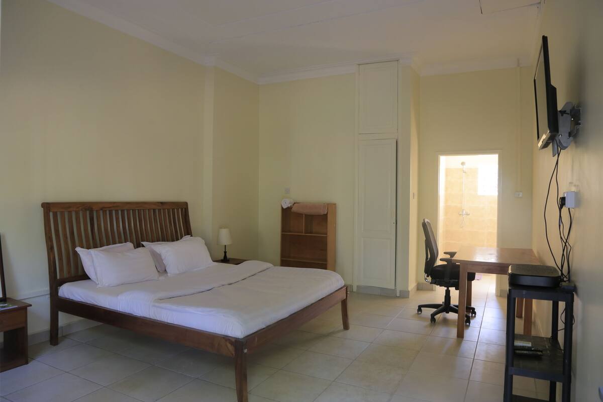 A bedroom with a wooden bed, a desk, and a chair.