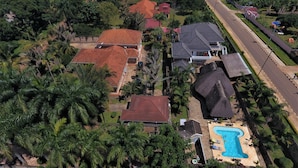 An aerial view of a residential area with houses, a swimming pool, and a road. - Entebbe Palm Hotel (Entebbe)
