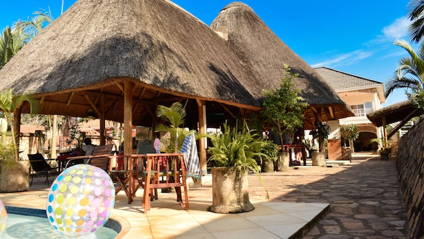A resort with thatched-roof structures, outdoor seating, and a swimming pool. - Entebbe Palm Hotel (Entebbe)