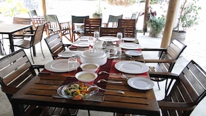 A dining table set with plates, bowls, and cutlery, surrounded by wooden chairs. - Entebbe Palm Hotel (Entebbe)