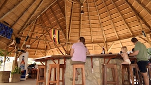 A rustic bar area with wooden stools and a thatched roof. - Entebbe Palm Hotel (Entebbe)