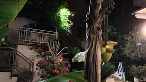 A nighttime garden with a staircase, potted plants, and a chair. - Noi Due Hotel (Rimini)